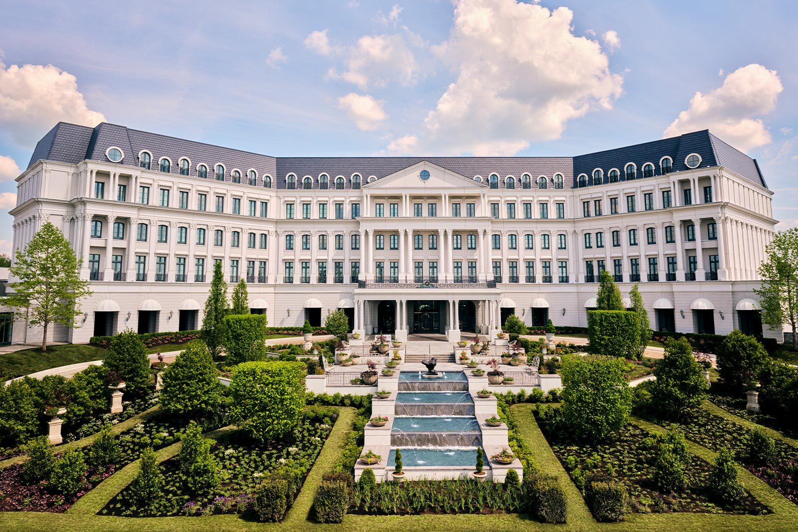 A grand view of The Chateau's luxurious exterior, showcasing its refined architecture and scenic surroundings, with lush green landscapes in the foreground.