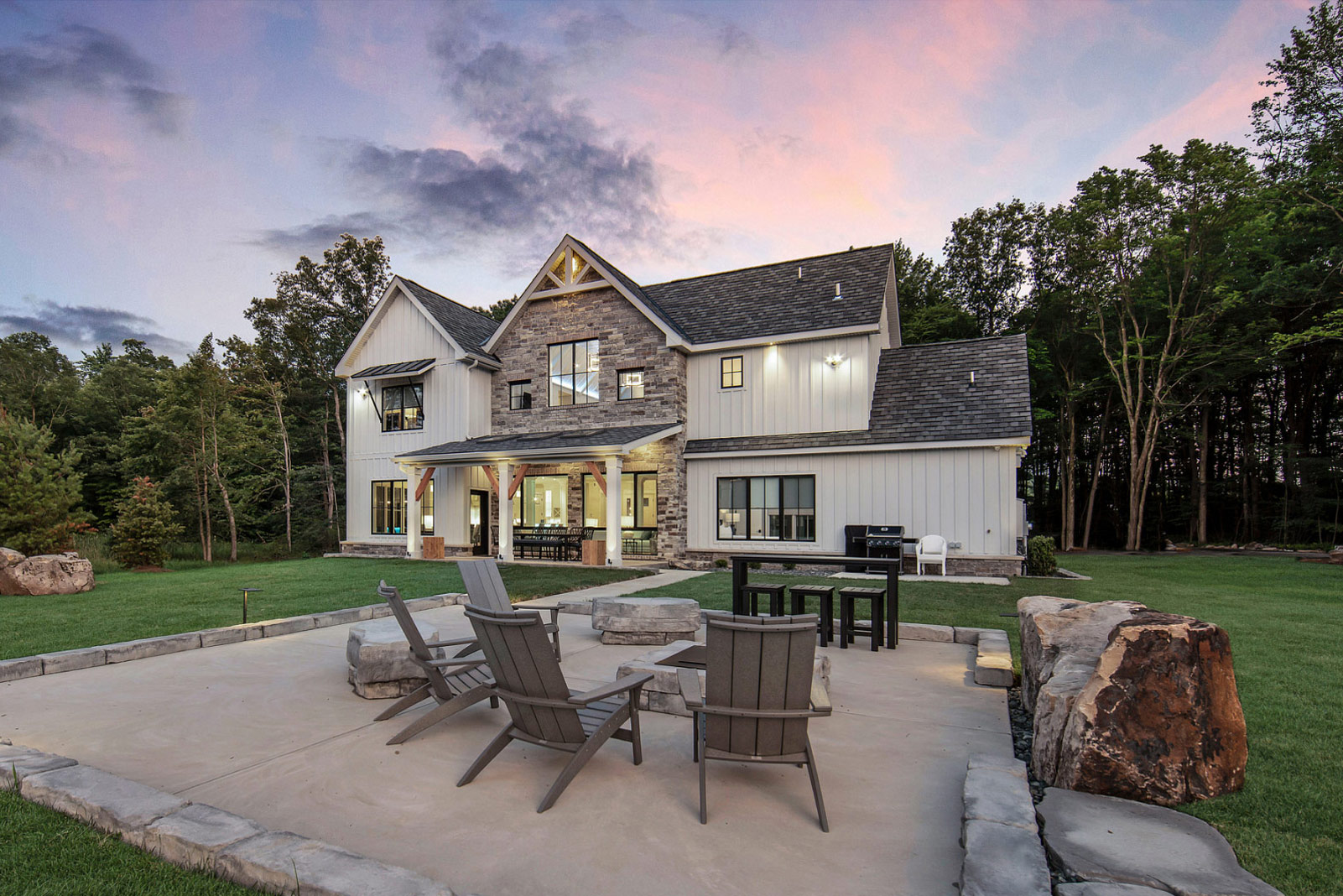 Outside view of a large home with the lights on in the house during sunset.