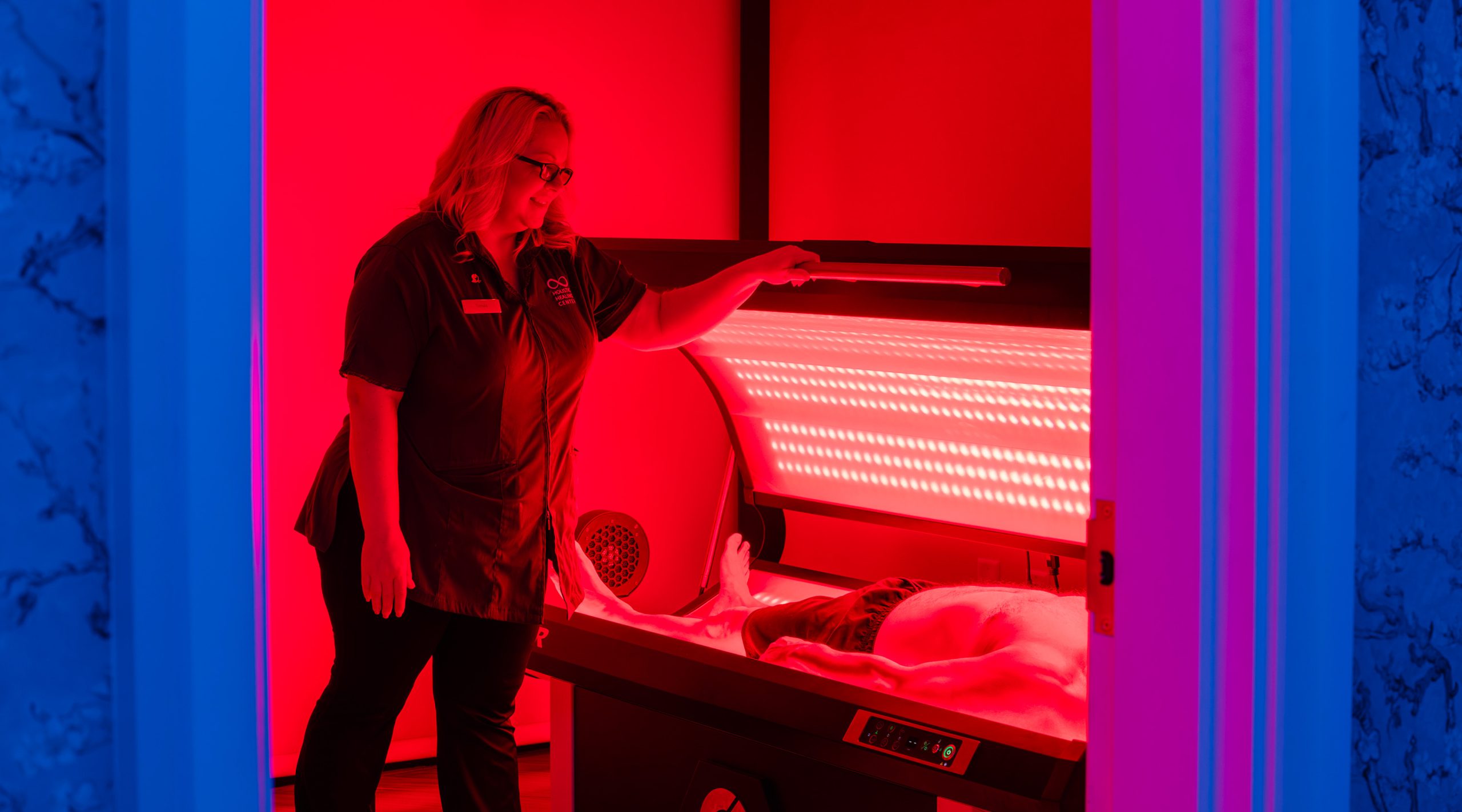 A female provider assisting a male client in a NovoTHOR PBM therapy using red and infrared light